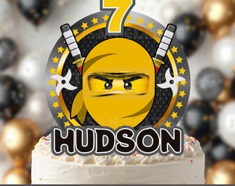 Puede incluir: Un adorno para tarta personalizado con un personaje ninja amarillo y el número 7. El diseño incluye espadas ninja y estrellas, con el nombre "HUDSON" en letras coloridas. También está presente el texto "PERSONALISED CAKE TOPPER PNG TRANSPARENT FILE".