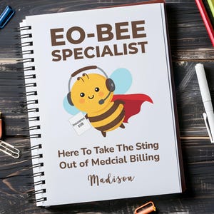May include: A spiral-bound notebook with a white cover featuring the text EO-BEE SPECIALIST, a cartoon bee wearing a headset and red cape holding a paper labeled Insurance EOB, the text Here To Take The Sting Out of Medcial Billing, and the name Madison.