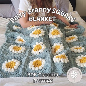 May include: A blue crochet blanket with a daisy pattern. The blanket is made with granny squares and has a white and yellow daisy design. The text "Daisy Granny Square Blanket" and "PDF Crochet Pattern" is visible on the blanket.