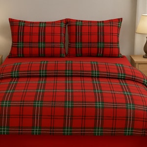 Può includere: Un completo letto a quadri rossi con dettagli verdi e bianchi. Il set include un copripiumino e due federe. Il letto è fatto con un lenzuolo con angoli rosso. La stanza ha due comodini in legno e lampade.