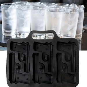 以下が含まれることがあります： ハンドガンの形をした黒いシリコン製氷皿、ハンドル付き。背景には氷と水で満たされた透明なグラスがいくつかあり、トレイの使用を示唆しています。トレイには6つの銃の形をした型があります。