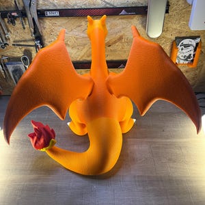 May include: An orange and yellow Charizard figure with outstretched wings and a fiery tail. The figure is posed on a wooden surface, showcasing its detailed design and vibrant colors. The figure is a popular character from the Pokemon franchise.