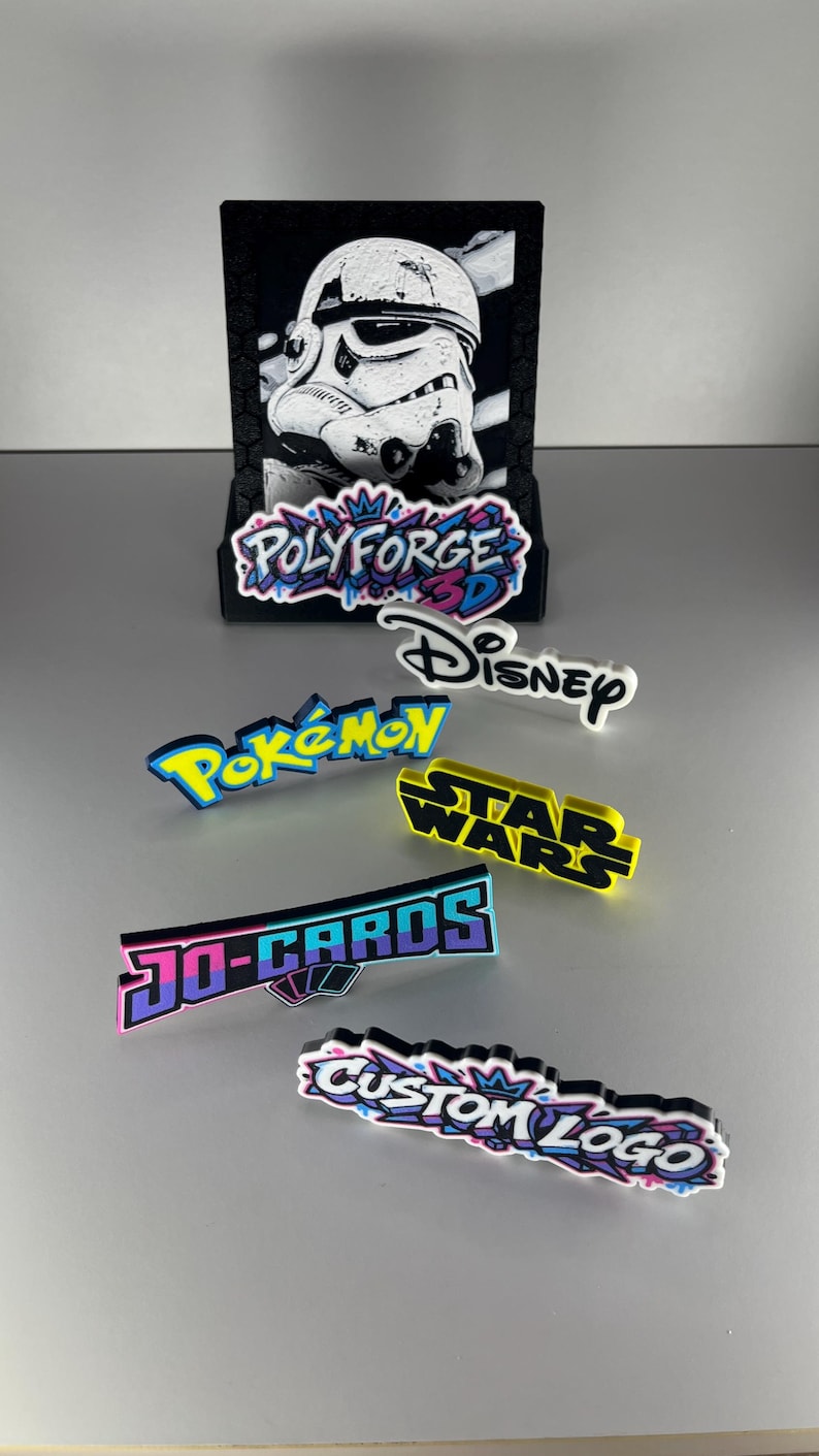 K&ouml;nnte beinhalten: Eine Sammlung von 3D-gedruckten Schildern und Logos, darunter ein schwarzer Aufsteller mit einem Stormtrooper-Bild sowie einzelne Schilder mit den Aufschriften PolyForge 3D, Disney, Pok&eacute;mon, Star Wars, Jo-Cards und Custom Logo in verschiedenen Farben.