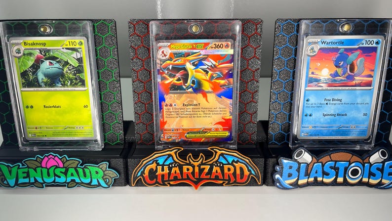 May include: Three trading card display stands featuring Bisaknosp, Mega Glurak Y-EX, and Wartortle cards in protective cases. Each stand has a hexagonal pattern background and a colorful base with the names Venusaur, Charizard, and Blastoise.