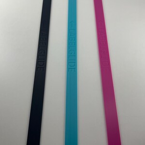 Peut inclure: Trois longues bandes rectangulaires et fines de couleur noire, bleu vif et magenta. Chaque bande pr&eacute;sente le texte en relief LABELGLIDE orient&eacute; verticalement sur toute la longueur, accompagn&eacute; d'une petite ic&ocirc;ne de fl&egrave;che pointant vers le texte.