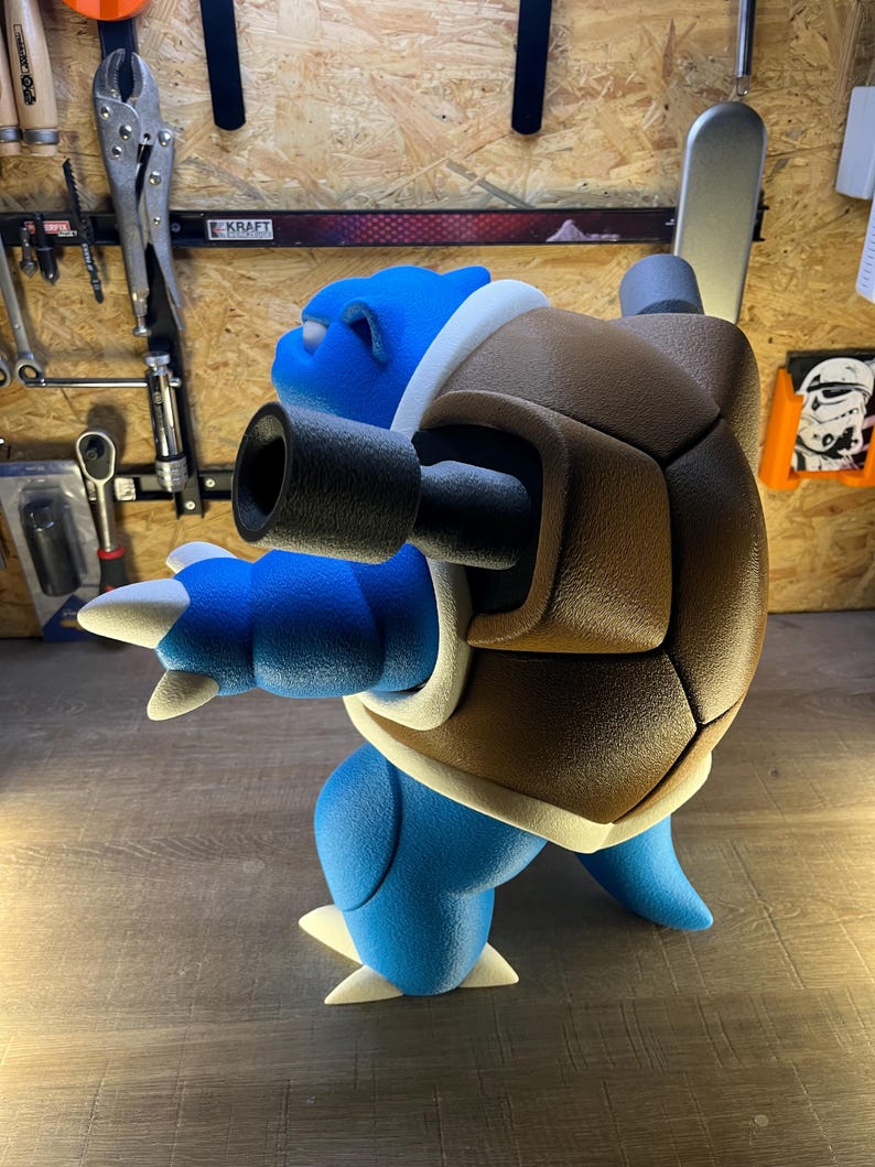 May include: A blue and brown Blastoise figurine, a Pok&eacute;mon character, is displayed in profile. The figurine features a blue body, a brown shell, and white accents. The figure has two cannons extending from its shell.