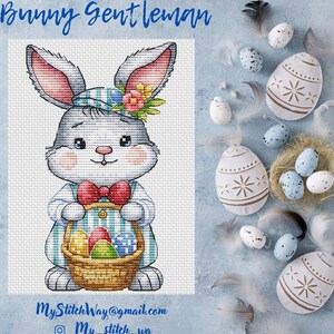 Puede incluir: Patrón de punto de cruz de un conejito sosteniendo una cesta de huevos de Pascua. El conejito lleva una camisa a rayas azul y blanca, una corbata de lazo roja y una corona de flores. El fondo es de color azul claro.