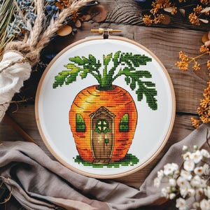 Puede incluir: Bordado de punto de cruz de una casa con forma de zanahoria con una parte superior verde frondosa y una puerta marrón. La casa está rodeada de hierba verde.