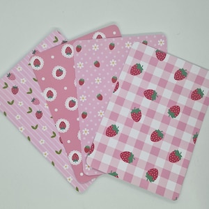 Peut inclure: Quatre cartes rectangulaires roses avec des motifs de fraises. Les motifs comprennent des rayures, des pois, du vichy et des fraises avec des accents de marguerites blanches. Les cartes sont disposées en éventail.