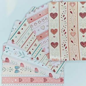 May include: A selection of Valentine's Day stationery. The designs feature hearts, floral patterns, and stripes in pink, red, and cream. The stationery includes envelopes and decorative paper.