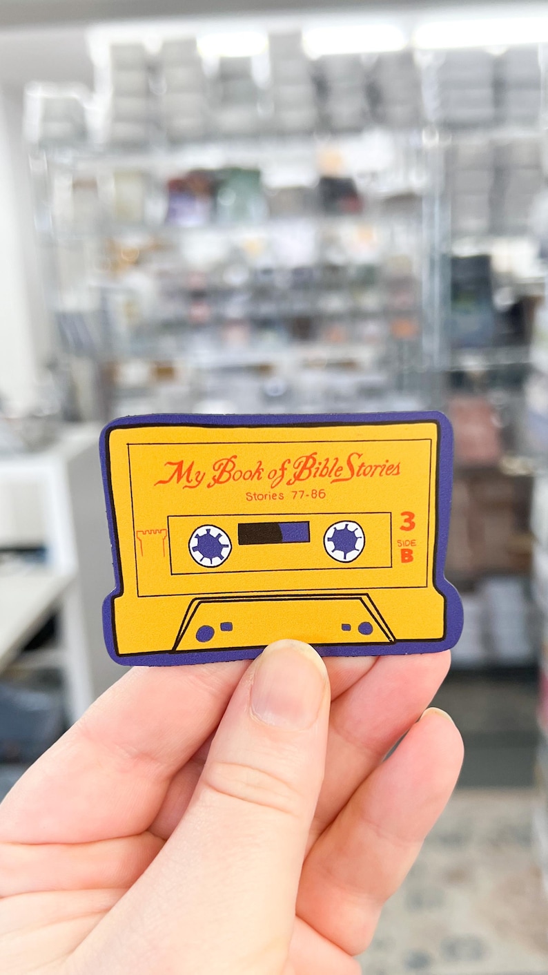 May include: Yellow and blue cassette tape sticker with the text "My Book of Bible Stories" and "Stories 77-85". The sticker has a blue border and a white cassette tape design.