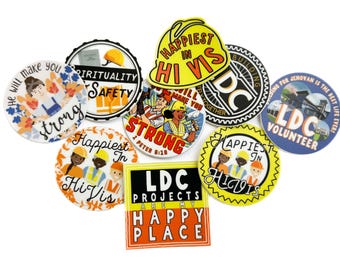 Puede incluir: Surtido de pegatinas redondas de colores con varios diseños y textos. Las pegatinas incluyen frases como "Happiest in Hi Vis", "Strong", "LDC Projects are my Happy Place", y "Building for Jehovan is the best life ever!"