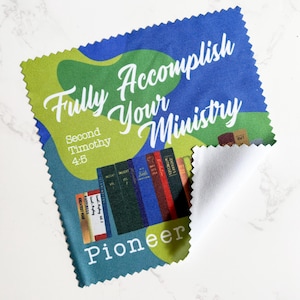 Puede incluir: Un paño de limpieza Pioneer azul, verde y blanco con el texto "Fully Accomplish Your Ministry" y "Second Timothy 4:5". El paño presenta un gráfico de libros y un borde blanco.