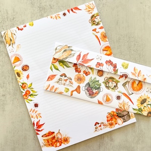 May include: A white letter writing set with a fall harvest theme. The set includes a letter sheet and envelope with a border of autumnal foods like pumpkins, corn, apples, and mushrooms.