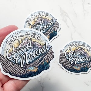 Może przedstawiać: Zestaw naklejek z g&oacute;rskim krajobrazem i napisem "DECLARE THE Good News!". Projekt obejmuje g&oacute;ry, drzewa i rzekę, z wschodem słońca w tle. Naklejki są białe z błyszczącym wykończeniem.