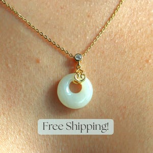 May include: A gold chain necklace with a white round pendant featuring a small gold heart charm. The pendant has a hole in the center.  Free Shipping!