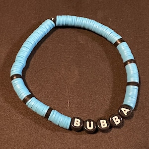 Könnte beinhalten: Ein blaues und schwarzes Perlenarmband mit dem Namen "BUBBA" in weißen Buchstaben auf schwarzen Perlen.
