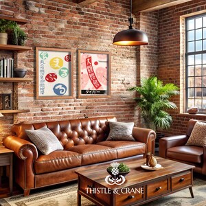May include: A living room featuring a brown leather sofa and armchair, a wooden coffee table, and a brick wall. Two framed Japanese art prints are displayed above the sofa. A lamp and shelves with books and plants complete the decor.