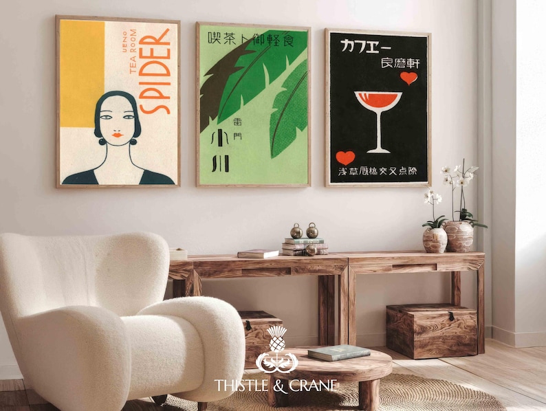 May include: Three framed vintage art prints. The first features a woman's portrait with the word "SPIDER". The second has green leaves and Japanese text. The third has a cocktail glass and Japanese text. The prints are displayed above a wooden console.