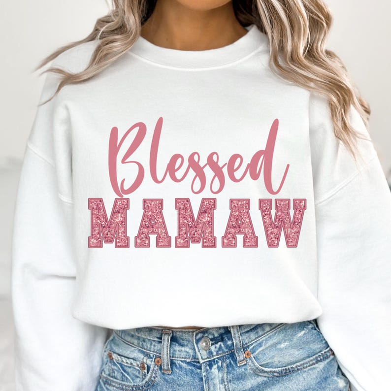 May include: White sweatshirt with the text "Blessed Mamaw" in pink glitter lettering.