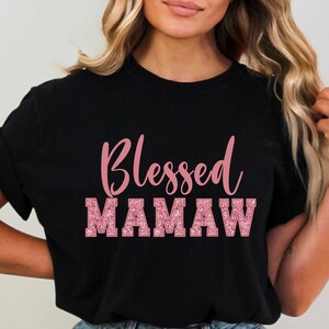 May include: Black t-shirt with the text "Blessed Mamaw" in pink glitter lettering.