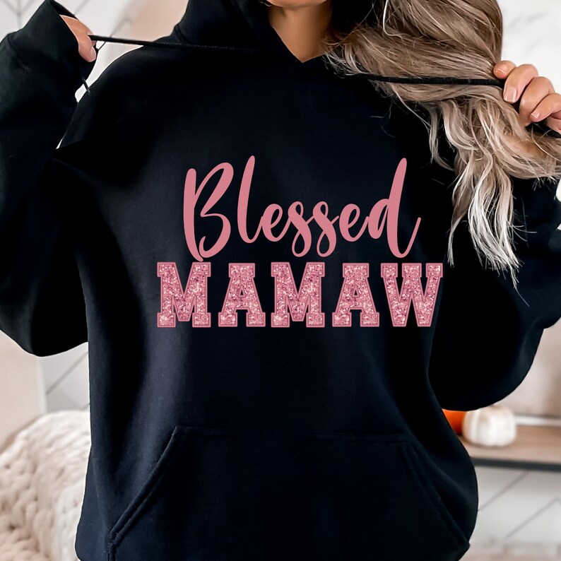 May include: Black hooded sweatshirt with the text "Blessed Mamaw" in pink glitter lettering.