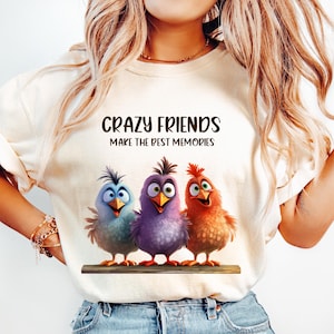 May include: A white t-shirt with the text "Crazy Friends Make The Best Memories" and a graphic of three cartoon birds. The birds are blue, purple, and orange.