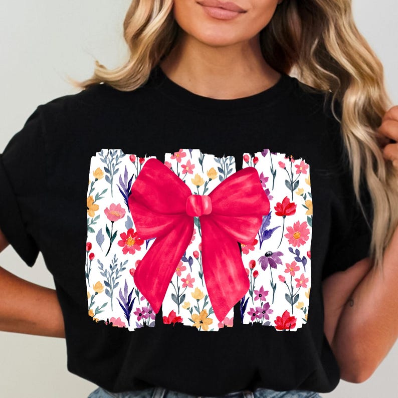 Peut inclure: T-shirt noir avec un grand n&oelig;ud rouge sur un motif floral. Le motif floral comprend des fleurs color&eacute;es et des feuilles vertes sur fond blanc. V&ecirc;tement d&eacute;contract&eacute;.