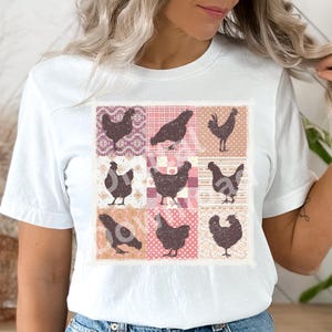 Pode incluir: Uma camiseta branca com um design de patchwork que apresenta silhuetas de galinhas em v&aacute;rias poses. O patchwork &eacute; em tons de rosa e marrom sobre um fundo branco.
