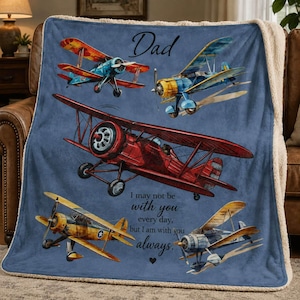 May include: A blue blanket featuring illustrations of vintage airplanes in various colors. The word "Dad" is at the top, with the text "I may not be with you every day, but I am with you always." printed below the airplanes. The blanket has a soft, white sherpa lining.