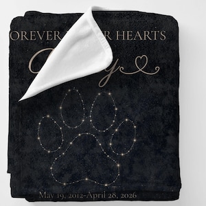 May include: Black blanket with a paw print design made of small, glowing dots. The blanket has the words "Forever in our hearts" and a name in a cursive font. The dates "May 19, 2012-April 28, 2026" are printed at the bottom.