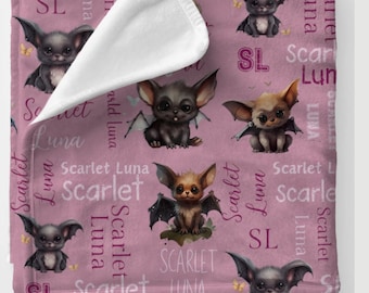 May include: A pink baby blanket with a repeating pattern of cute cartoon bats with wings and the names "Scarlet" and "Luna" in pink script.