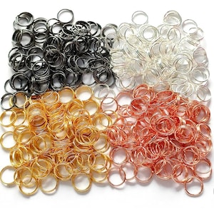 May include: A collection of small metal jump rings in black, silver, gold, and copper. These round rings are ideal for jewellery making or crafts. The image provides a close-up view, with each colour of ring grouped together.