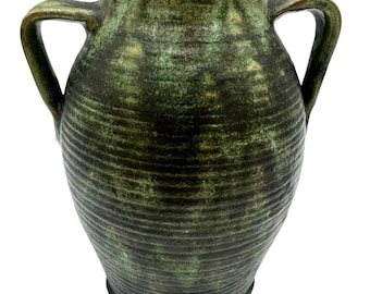 May include: A green ceramic vase with two handles. The vase has a textured, ribbed surface and a dark green and brown color scheme. The vase is a decorative item.