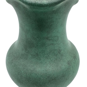 Può includere: Un vaso in ceramica verde con un bordo a festoni. Il vaso ha una superficie testurizzata e un corpo arrotondato.