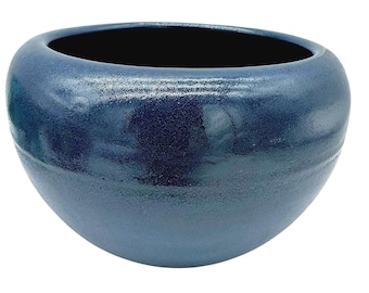 May include: A handcrafted, deep blue ceramic bowl with a wide opening and rounded shape. The bowl has a textured surface and a dark interior. This decorative bowl is suitable for various uses.