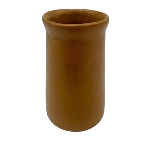 Könnte beinhalten: Eine zylindrische, braune Keramikvase mit leicht ausgestelltem Rand. Die Vase hat eine glatte, matte Oberfläche und ein schlichtes, minimalistisches Design. Die Vase ist etwa 15 cm hoch.