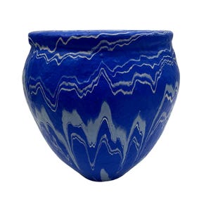Könnte beinhalten: Ein blauer Keramiktopf mit einem wellenförmigen weißen Muster. Der Topf hat eine abgerundete Form mit einem leicht ausgestellten Rand. Das weiße Muster erzeugt einen Marmoreffekt auf der blauen Oberfläche.