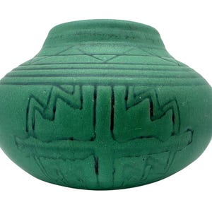 Könnte beinhalten: Eine grüne Keramikvase mit rundem Körper und leicht ausgestelltem Rand. Die Vase weist geätzte geometrische Muster, darunter Zickzack- und lineare Designs, in einem dunkleren Grünton auf. Die Gesamtform erinnert an einen kleinen, handgefertigten Topf.
