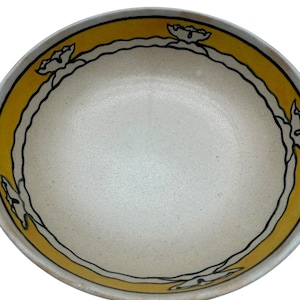 Könnte beinhalten: Eine Keramikschale mit cremefarbenem Innenraum und gelbem Rand. Der Rand ist mit einer schwarzen Linie und blütenartigen Formen verziert. Die Schale hat ein schlichtes, aber elegantes Design.