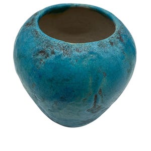May include: A turquoise ceramic vase with a textured, crackled surface. The open-topped vessel has a rounded shape with a slightly irregular form. The interior is a contrasting brown color, creating a striking visual contrast. The vase is suitable for home decor.