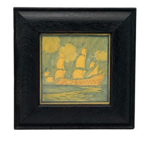 May include: Framed artwork featuring a sailing ship with yellow sails and a brown hull, set against a blue-green background. The artwork is enclosed in a square, black wooden frame, adding a classic touch to the nautical scene.