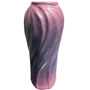 May include: A ceramic vase with a textured, swirling vertical pattern. The surface features a gradient color transition, shifting from a deep purple at the base to a vibrant magenta pink at the top, with a subtle shimmering finish throughout the exterior.