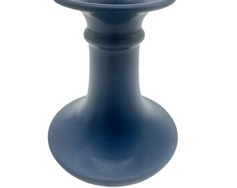 May include: A matte navy blue candle holder with a wide, flared top rim, a slender neck featuring a single horizontal ring detail, and a rounded, bulbous base. The object has a smooth, uniform finish and a symmetrical, vertical structure.