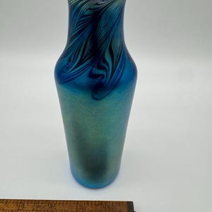 May include: A blue iridescent glass vase with a feathered pattern. The vase is approximately 6 inches tall.