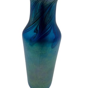May include: A blue iridescent glass vase with a swirling feather pattern. The vase has a narrow neck and a wide base.