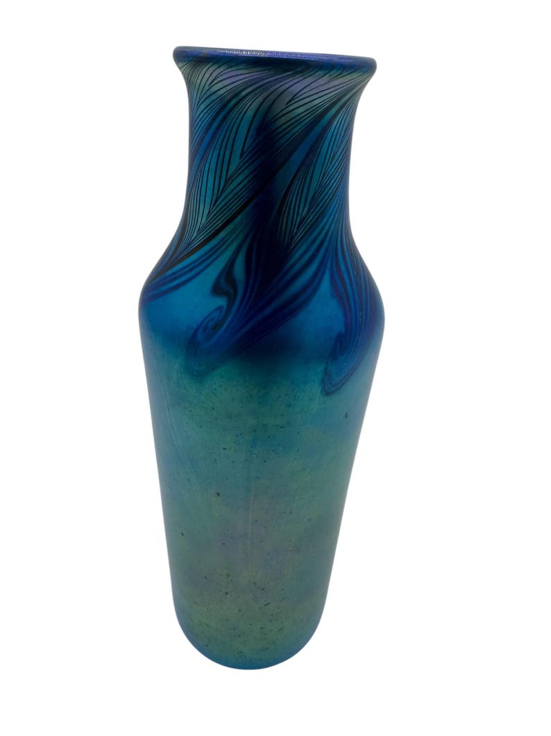 May include: A blue iridescent glass vase with a swirling feather pattern. The vase has a narrow neck and a wide base.