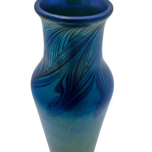 May include: A blue glass vase with a swirling, feathered pattern. The vase has a narrow neck and a wide base.