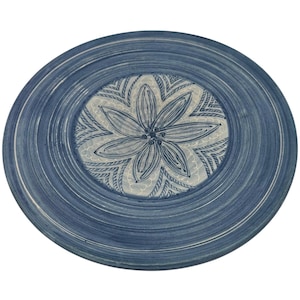 Könnte beinhalten: Ein runder, blauer Keramikteller mit einem Blumendesign in der Mitte. Der Teller hat ein handgemaltes Aussehen mit konzentrischen Ringen in verschiedenen Blautönen. Das zentrale Design zeigt eine stilisierte Blume in Blau- und Weißtönen.