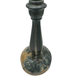 May include: A ceramic candlestick holder featuring a tall, slender stem and a wide, circular base. The piece is finished in a glossy glaze with blended tones of deep charcoal gray, slate blue, and earthy tan, showcasing a smooth, reflective surface.